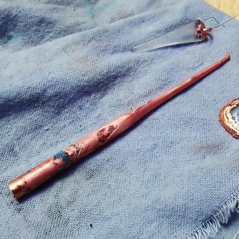 A copper rod lying on a blue rag. The rod looks more like a cone