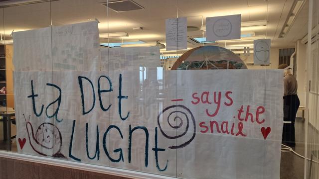 Klassrum sett utifrån. En stor handritad skylt med texten "Ta det lugnt – says the snail".