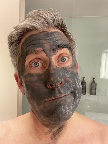man with an exfoliating face mask on - selfie