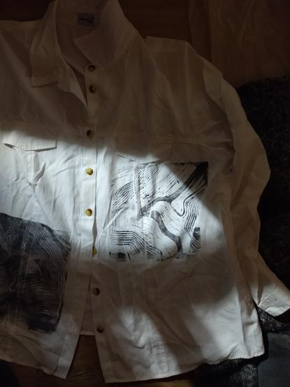 a picture of a white shirt with a linocut print of a bird with extended wings.