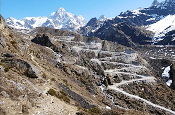 Road construction in 2019 created steep switchbacks over the Tiptola Pass (5095 m) from Nepal to Tibet.  Tall mountains in the background.
