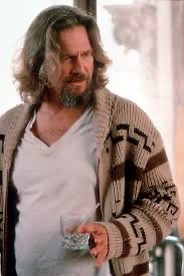 The Dude (Jeff Bridges) in his trademark v-neck t-shirt and light brown knit cardigan with dark brown and black geometric pattern