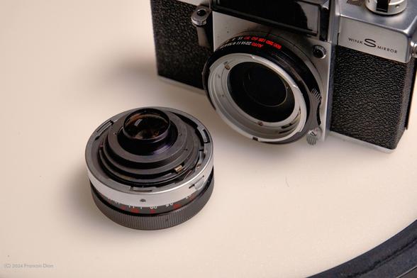 j slot tabs on the mount of the lens. Lens is separated from the camera, both against a white background