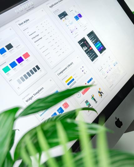 Zrobione pod kątem zdjęcie ekranu monitora na którym jest program Locus Design System z otwartymi oknami i zestawieniami różnych komponentów graficznych, jak testy, kolory itd. Zdjęcie pochodzi z Unsplash od Balazsa Ketyi (https://unsplash.com/photos/silver-imac-9VzoRKfBsMM).