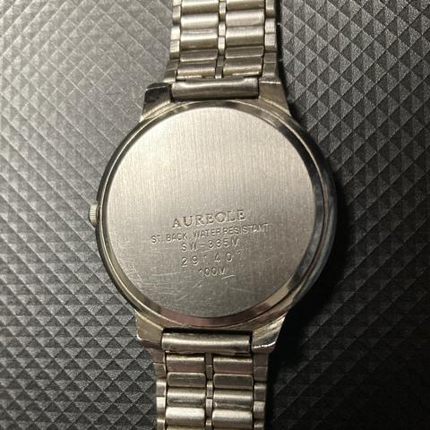 ステンレスのケースとバンドの腕時計の裏面の画像。AUREOLE / ST.BACK . WATER RESISTANT / SW-335M などと刻まれている。