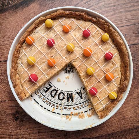 A photo of the same pie, seen from above and with about a quarter cut out. The missing slices expose a decorative pie dish, with a bistro-tile print and the letters 'a mode' visible.