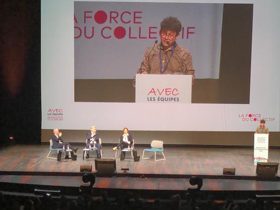 2 coprésidents d'AVEC santé encadrent le ministre sur scène. Le troisième parle au pupitre.