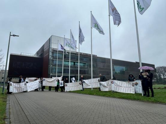 Een groep mensen met banketstaaf waarop de namen van vermoorde Gazanen staan, staat voor het gebouw van KPMG.