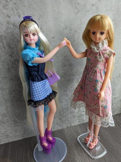 Two fashion dolls side by side. The one on the left is Takara Tomy's Jenny and has long blonde hair down to her ankles with a sky blue streak of colour on the inside. The one on the right is Takara's Barbie (which was rebranded as Takara's Jenny) and has slightly darker blonde hair.