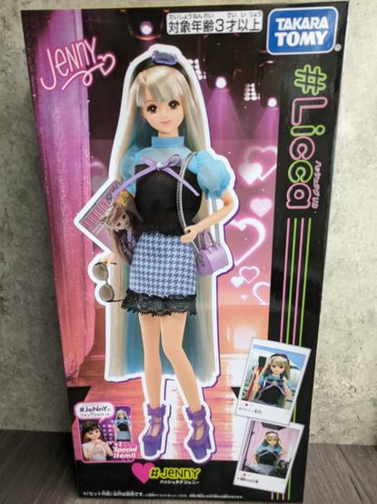 The Hashtag Jenny doll, in package. There is a photo of the doll as well as several Polaroid-style snapshots of the doll at various fashion shoots.