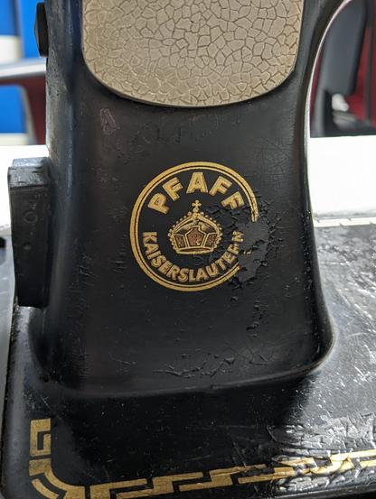 The round Pfaff logo on the back side is drawn with gold paint too, but a chunk of the outside circle is missing.