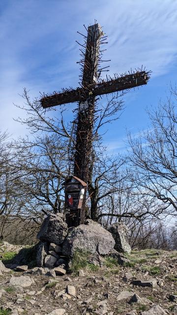 Near the top of the hill Klokoč is a wooden cross, its base is secured with rocks. The cross is covered with hundreds of nails of different sizes, inserted depth and state of rust. Iron box shaped like post box covered with stickers is also present near the base.