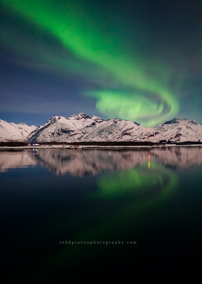 Stunning green Northern Lights over the waters and snow-covered mountains of Prince William Sound near Valdez, Alaska.