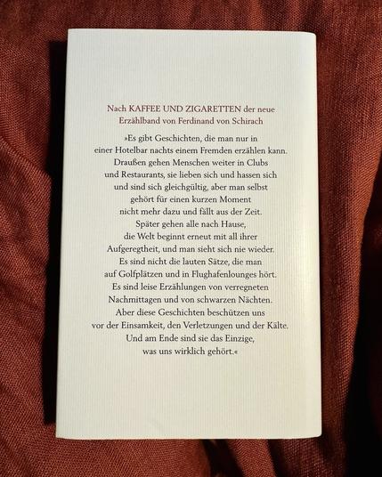 Buchrückseite „Nach KAFFEE UND ZIGARETTEN der neue Erzählband von Ferdinand von Schirach
»Es gibt Geschichten, die man nur in einer Hotelbar nachts einem Fremden erzählen kann.
Draußen gehen Menschen weiter in Clubs und Restaurants, sie lieben sich und hassen sich und sind sich gleichgültig, aber man selbst gehört für einen kurzen Moment nicht mehr dazu und fällt aus der Zeit.
Später gehen alle nach Hause, die Welt beginnt erneut mit all ihrer Aufgeregtheit, und man sieht sich nie wieder.
Es sind nicht die lauten Sätze, die man auf Golfplätzen und in Flughafenlounges hört.
Es sind leise Erzählungen von verregneten Nachmittagen und von schwarzen Nächten.
Aber diese Geschichten beschützen uns vor der Einsamkeit, den Verletzungen und der Kälte.
Und am Ende sind sie das Einzige, was uns wirklich gehört.«“