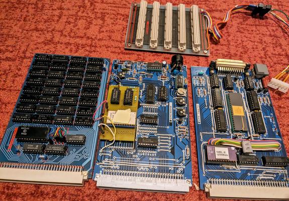 3 cartes format Europe avec des connecteurs din41612. De gauche à droite : 4Ko RAM avec 32 RAM 256*4 2112, interface cassette, et micro-ordinateur BASIC SC/MP. En haut le fond de panier universel Elektor