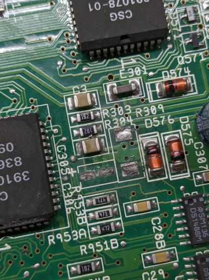 Closeup of a capacitor and resistor pads on an A600 motherboard. The pads are dull, crusty, cracked