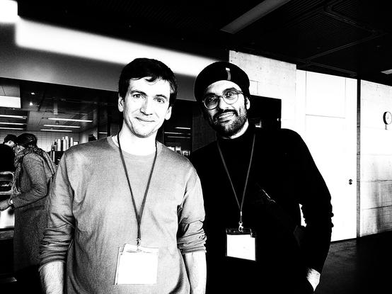 Black and white image of two Hackathon participants at a canteen. Photographed by Magdalena Gneist