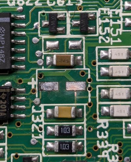 Closeup of an SMD electrolytic capacitor pad on an A600 mobo. The pads are clean, but the one on the right has a minuscule interruption between pad and trace reaching it
