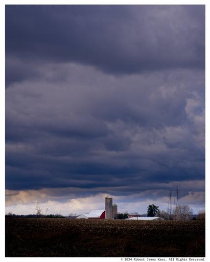 Expansive dark sky with a small patch of illumination of an isolated silo.