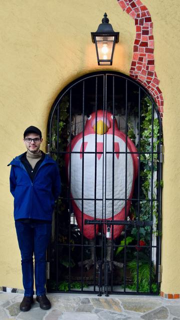 Full body photo of me beside a life size statue of a Parakeet from Studio Ghibli’s latest film “The Boy and the Heron”. The Parakeet is in a cage, but standing tall with its chest out. I’m imitating its pose 🤪