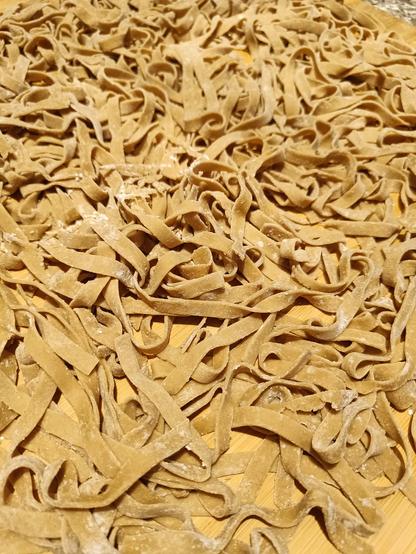 Tagliatelle di farina di castagne appoggiate su un tagliere e infarinate per fare in modo che non si appiccichino