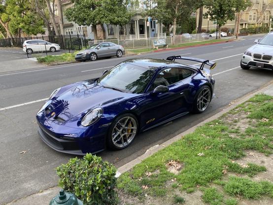 Front 3/4 view of a blue Porsche 911 GT3 with yellow accents as seen parked on a street.
