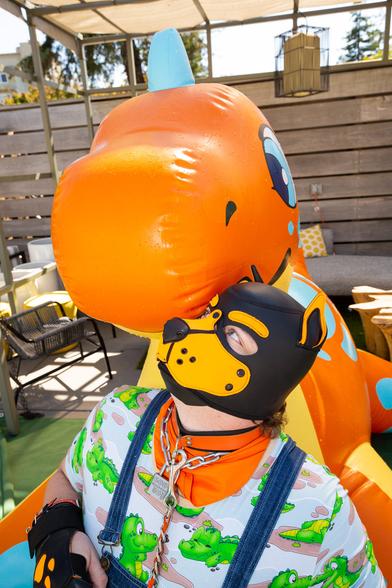 Me in my orange pup gear nuzzling up against the PuffyPaws Speckles Dino in a poolside cabana.