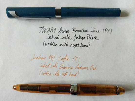 Two pens on a sheet of paper. The top pen is a dark blue-green with a curvy matt silver clip and a band of clear plastic in the middle. 
Beneath it is written, in black ink and somewhat shaky cursive, "TWSBI Swipe Prussian Blue (EF) inked with Jinhao Black (written with right hand)."
Below that is written, in orange ink and a less ornate but tidier sloped handwriting, "Jinhao 992 Coffee (F) inked with Diamond Autumn Oak (written with left hand)."
Below that is a translucent orange-brown pen with a silvery band in the middle and a silvery clip.