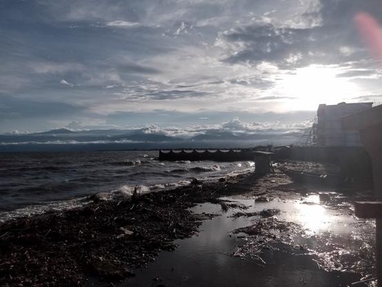 Sunsubiro super la Tanganjika lago - la ĉielo estas minacanta. Oni vidas ankaŭ ke la akvo inundas la strandon