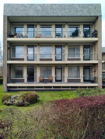 Facade of a flat with 3×3 appartements with balconies on a green lawn.