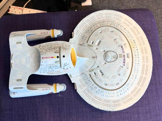 Galaxy class model upside down on a purple footstool