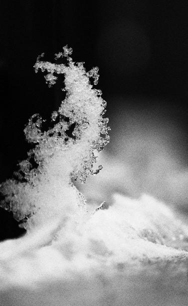 Melting snow resting on a counter ledge has gradually melted and formed a perpendicular, curved abstract of ice and snow crystals.