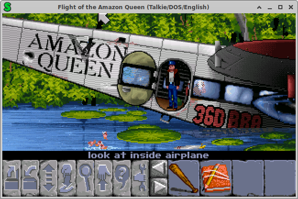 Game screenshot. The actions, such as open, close, use are displayed as icons at the bottom. Some random items, baseball bat, diary, are displayed to the right of that. The main part of the screen is the back of a plane, in water. At the left we see the tail, other than the empennage. A character with jeans, jacket and hat stands in the open hatch doorway, about in the middle of the screen. Towards the right are the wings, at the top of the plane. The tail says "Amazon Queen". The water has large lily-pads. And there are trees behind.