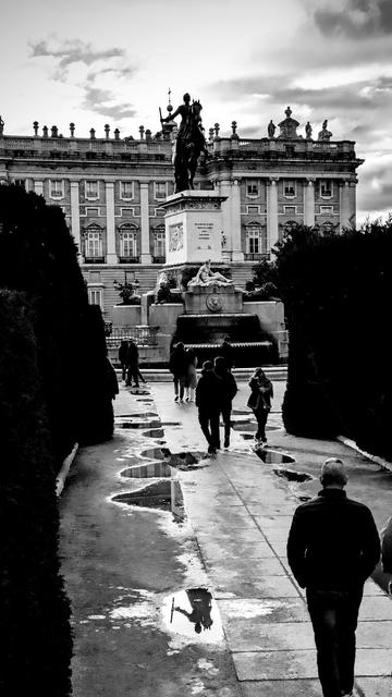 blanco y negro, vertical. plaza de oriente de Madrid, palacio real al fondo, estatua ecuestre de Felipe IV y su reflejo en un charco