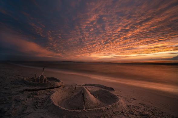 Long exposure of the sea and sand castles on the beach during a beautiful sunset in the autumn