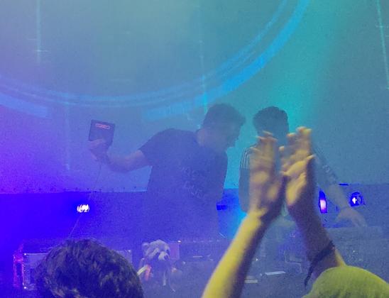 Hoffman holding up a small monitor showing an Amiga "Guru Meditation" error during the DJ set.