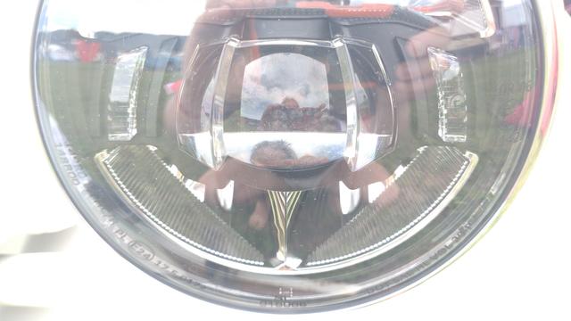 Close-up the bottom 2/3 of a round LED headlight with quite some non-round lenses in it.