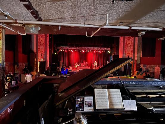 Foreground: beatrun grand piano in what used to serve as the techie booth for concerts.
Background: band on stage lit by red lights
On each side: functioning permanent quarter pipes where skaters play during non-concert hours