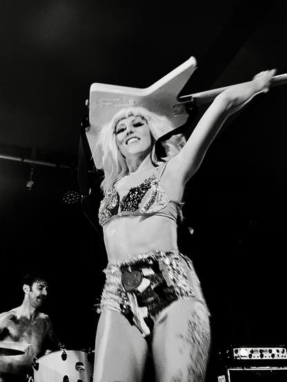 The Soapgirls' Camille "Mille" Debray performs live on stage with her bass over her head.