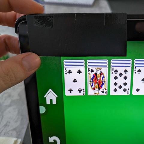 The same tablet corner close-up, but with the cardboard piece flipped down. It now exactly covers the ad in the corner of the screen.