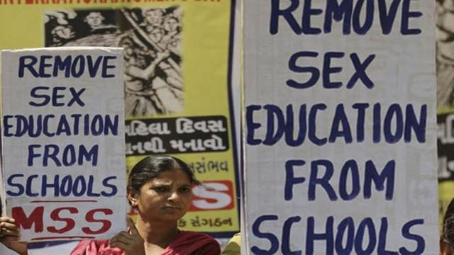 photo of a woman holding a sign reading "remove sex education from schools," standing next to other similar signs