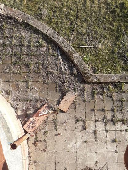 Eine Mauer von oben, die einen Halbkreis beschreibt mit einer gepflasterten Fläche diesseits und Wiese jenseits.
