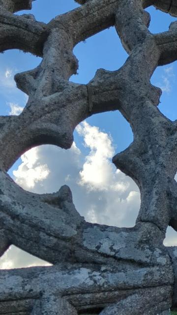 Vue du ciel a travers un vitrail cassé. Il ne reste que le granit plein de lichen