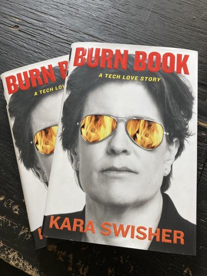 Black and white image of a person with aviator sunglasses on that have colored flames reflected in them