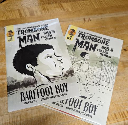 Two comic books on a table. Both are "Trombone Man" issue #1. One with regular and one with special limited edition cover.