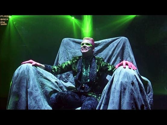 Edward Nigma sitting in a chair with a green beam going into his head.