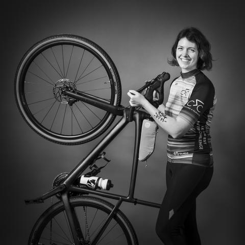 Photo en noir et blanc, je me tiens à côté de mon vélo que je soulève à la verticale, les mains sur les freins, une inscription au marqueur noir sur l'avant-bras : 354 PPM