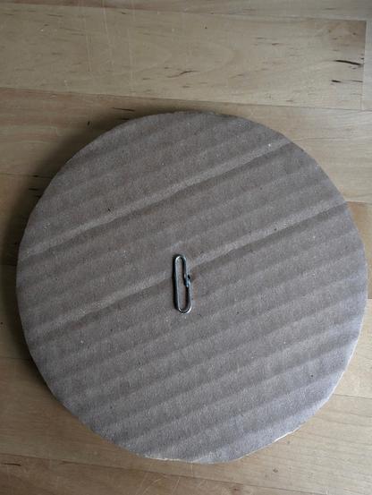 Cardboard circle with half a paperclip in the centre.