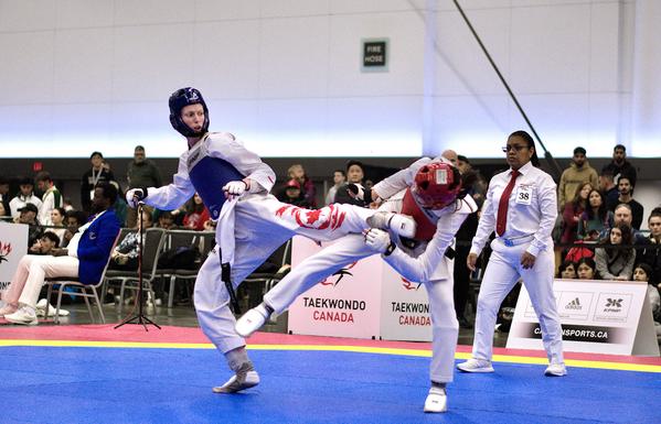 Josipa Kafadar wearing blue kicks an opponent at the Taekwondo Canada Olympic qualifying event, November 2023