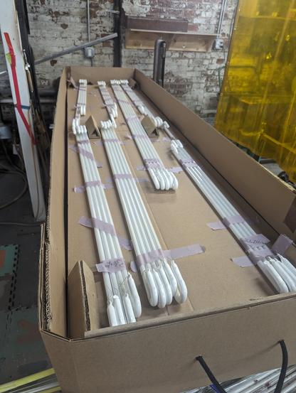 bundles of neon straight tubes taped together and taped to cardboard layered in a giant, 8.25 foot ride flat box.